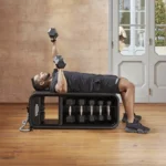 Technogym Home workout bench with dumbbells, elastic bands, and weighted knuckles